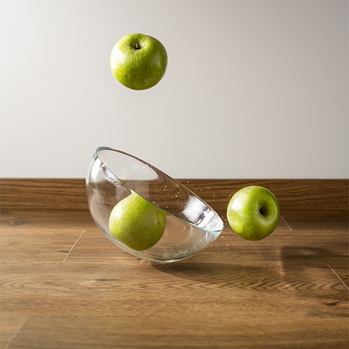 glasskål med æbler falder ned på et brunt Rigid-vinylgulv fra Pergo
